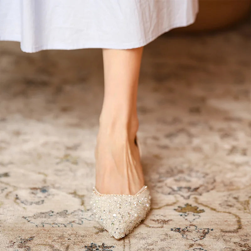 Close-up of a woman's feet wearing sparkly high heels on a patterned carpet.