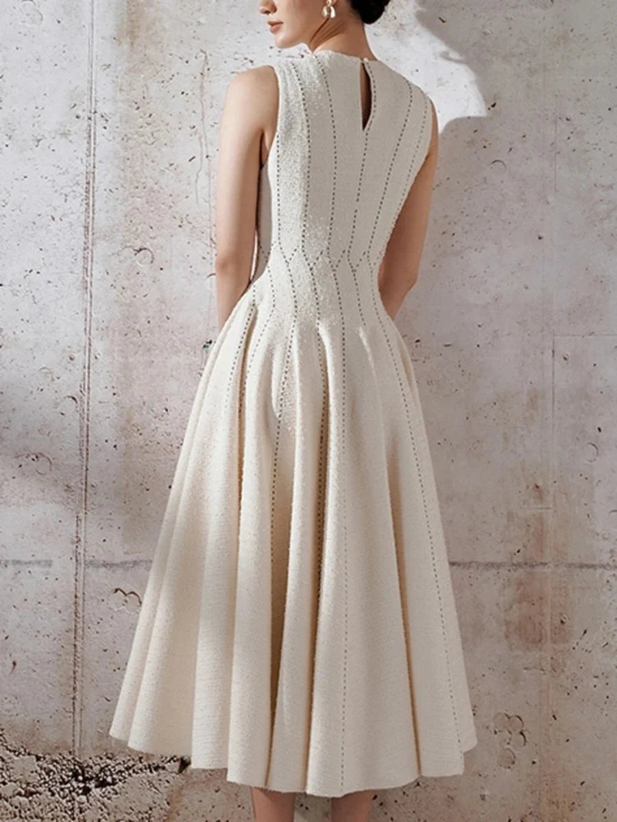 White dress with intricate back design against a textured wall.